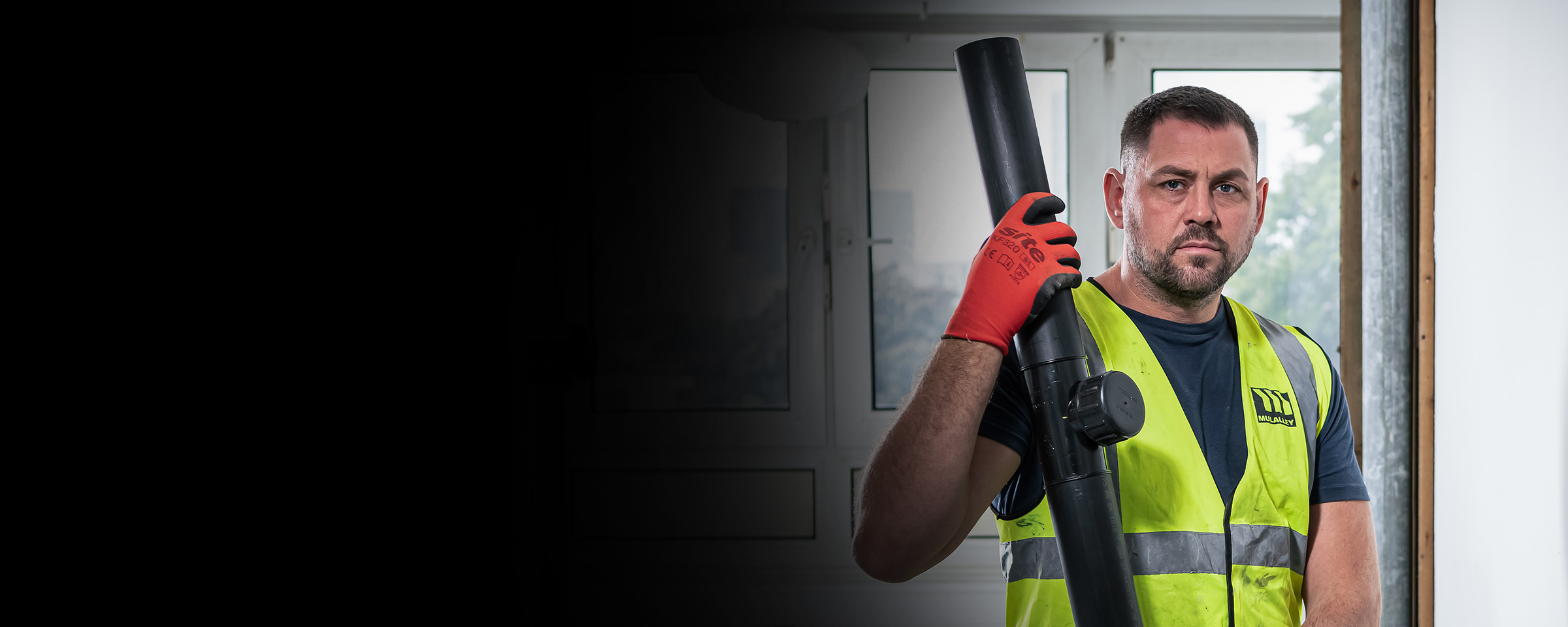 workman in hi-vis holding a black pipe